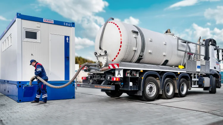 Saugfahrzeug entleert Abwassertank unter Container