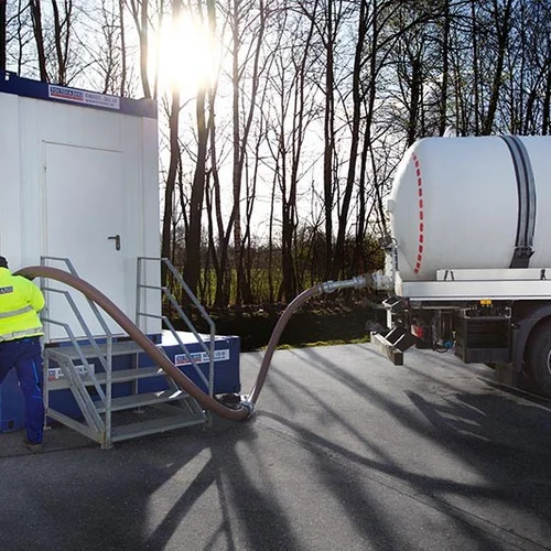 Saugfahrzeug entleert Abwassertank unter Sanitärcontainer