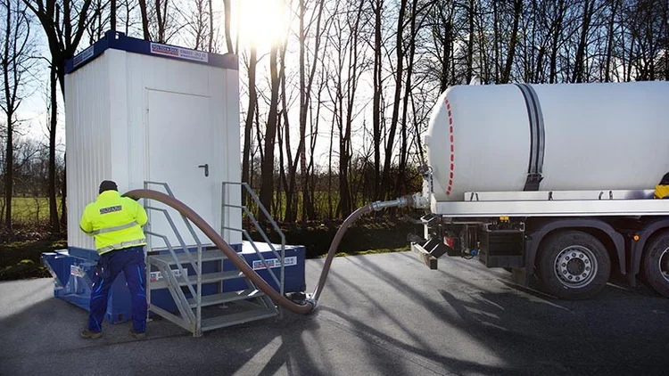 Saugfahrzeug entleert Abwassertank unter Sanitärcontainer