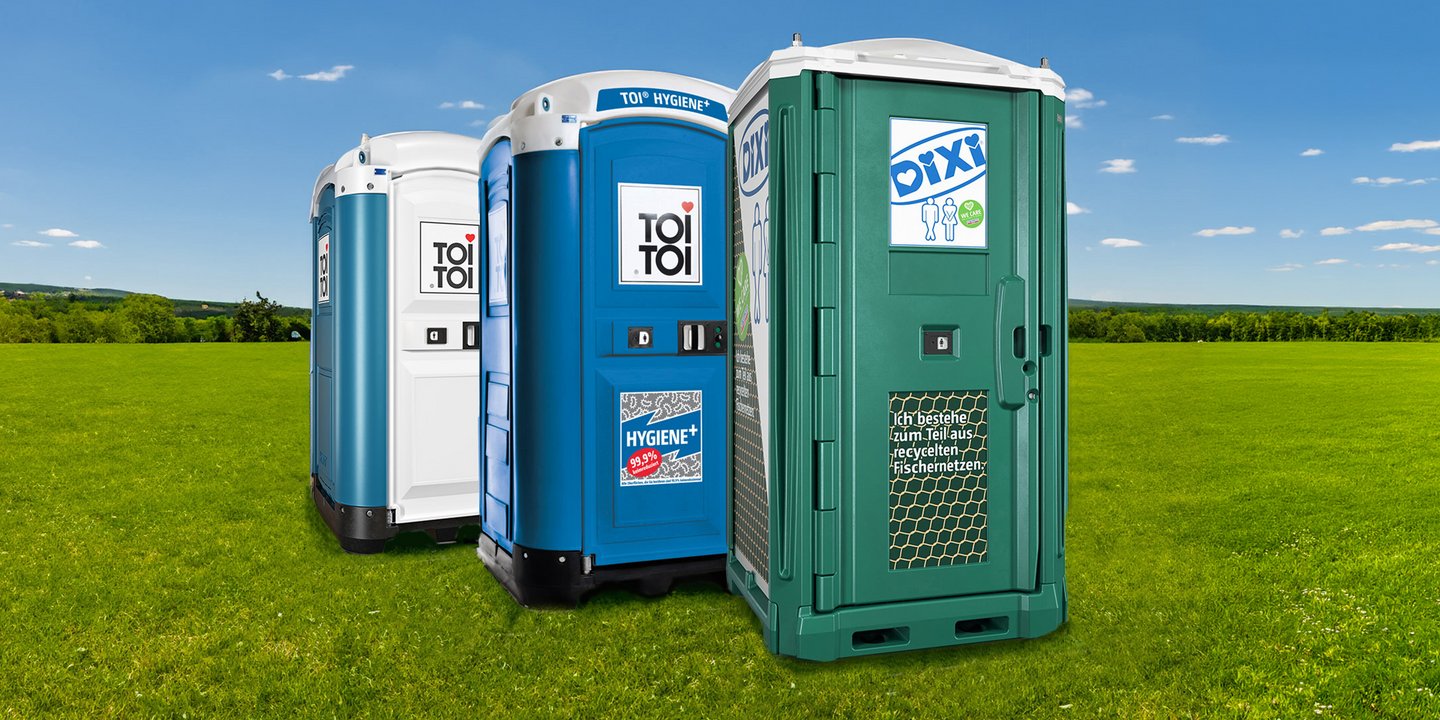 Drei Toilettenkabinen auf einer grünen Wiese
