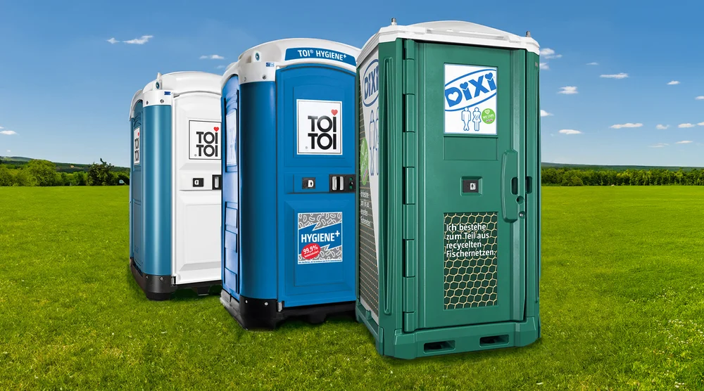 Drei Toilettenkabinen auf einer grünen Wiese