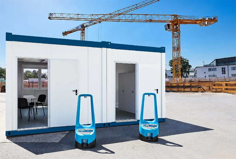 Zwei Handdesinfektionsspender TOI CARE vor einem Raumcontainer auf einer Baustelle